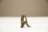 Vintage handmade African bronze monkey sculpture with aged patina, side view.