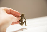 Small vintage African bronze sitting monkey sculpture held in hand, showing fine detail.