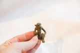 Hand holding small handmade African bronze monkey figurine, highlighting its unique texture.