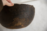 Vintage African wooden bowl held by hand, revealing dark, aged wood texture.