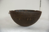 Dark brown vintage African wooden bowl with etched geometric patterns and metal ring.