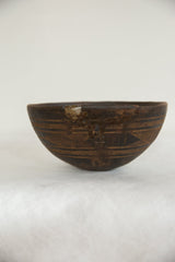 Vintage African wooden bowl with carved geometric patterns and visible aged chip on the rim.