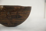 Vintage African wooden bowl, dark wood with etched linear patterns and aged patina.