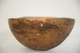 Aged African wooden bowl detail, showing rustic texture, uneven rim, and visible hole.