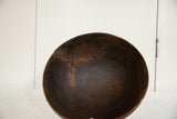 Inside a dark vintage African wooden bowl, highlighting the storied repair effort with staples.