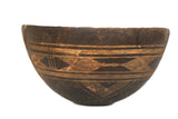 Vintage African wooden bowl with carved light geometric patterns and dark aged wood.