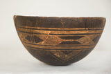 Upper rim of the dark vintage African wooden bowl with engraved geometric pattern.