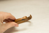 Hand holding rounded antique African copper bracelet, revealing its aged copper patina.