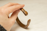 Hand-held antique African copper bracelet, showcasing its unique curved form and rich patina.