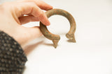 Hand-held bronze bracelet showcasing its rich, time-softened patina and pointed end.