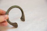 Curved vintage African bronze bracelet held in hand, with rich green-brown patina.