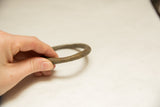 Vintage African bronze bracelet held by hand, revealing its time-softened patina.