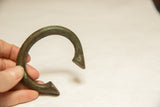 The curved form and time-softened green patina of a collectible African bronze bracelet.