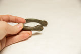 The weathered texture and hand-forged rounded end of a vintage African bronze bracelet.