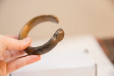 Aged patina and worn texture on the rounded terminal of an antique bronze cuff.