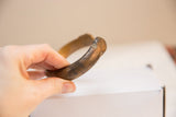 Angled profile of an antique bronze cuff showing its substantial curve and aged patina.