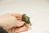 A hand holding the small bronze monkey sculpture to show its collectible scale and patina.