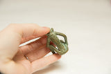 The textured back and oxidized green patina of the vintage bronze monkey sculpture.