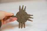 Hand holding a vintage African bronze crocodile head medallion, showing its handmade texture.