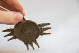 Vintage African bronze medallion held by hand, highlighting its textured surface and rich patina.
