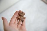 Vintage carved wooden person pendant held in hand to show its small scale.