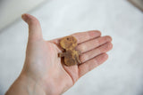 A small vintage wooden person pendant held in hand to show its handmade texture and scale.