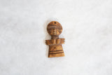 The stylized form and carved details of a vintage wooden African person pendant.
