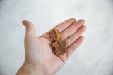 Handmade wooden African person pendant held in an open palm to show scale.