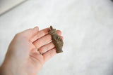 Vintage African bronze pendant held in hand, showing its size and tactile, handmade quality.