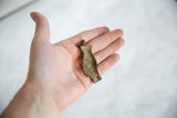 Handmade vintage African bronze pendant held in palm, showing its size and aged patina.