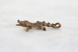 Profile view of a vintage bronze crocodile pendant with a rustic, handmade texture.