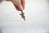 A hand holds the vintage bronze crocodile pendant to show its scale and handmade detail.