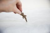 A hand holding a small, vintage African bronze crocodile pendant to show its scale.