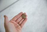Vintage African Baule bead with coiled details held in a palm for scale.
