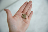 A vintage African Baule bead held in the palm of a hand for scale.