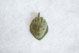 Oxidized bronze African mask pendant with textured, hand-sculpted details.