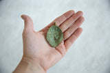 The concave interior of a handmade bronze pendant showing its textured green patina.