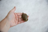 Handmade African bronze mask pendant held in the palm to show its size.