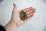Back of the handmade African bronze pendant showing its concave shape and rustic texture.