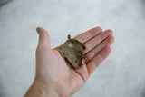 Concave back of a vintage African bronze mask pendant showing aged patina.