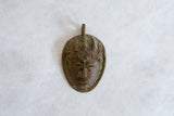 A detailed overhead view of the vintage African bronze mask pendant showing its aged patina.