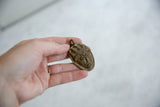 Vintage African bronze mask pendant held in hand, showing scale and handmade details.