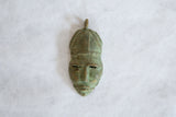 Vintage African bronze mask pendant with a rich green patina and textured surface.