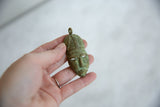Handmade African bronze mask pendant held in hand showing its collectible size and texture.