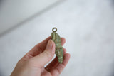 Side profile of a vintage African bronze pendant showing its aged patina and form.