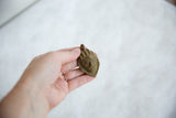 Vintage African bronze mask pendant held by hand to show its unique texture and scale.