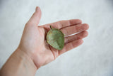 The concave interior of a vintage African bronze mask pendant with green patina.