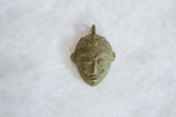 The unique, weathered texture and handmade details of the vintage bronze mask pendant.