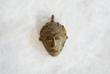 Close-up of the vintage bronze pendant's face, showing fine details in the headdress and aged finish.
