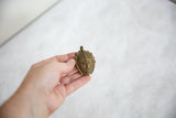 Vintage African bronze mask pendant held in hand to demonstrate its size and handmade texture.